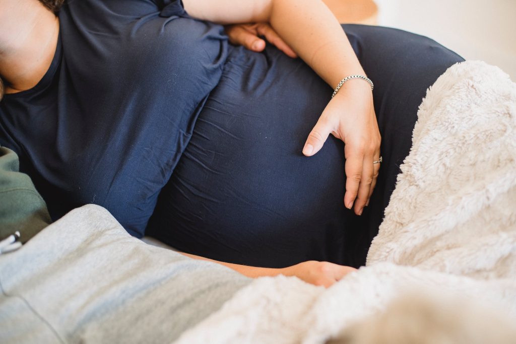 Zwangere vrouw die comfortabel slaapt met een ondersteunend zwangerschapskussen onder buik en rug